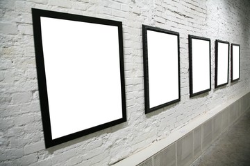 row of black frames on white brick wall