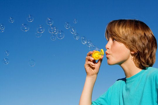 happy child playing blowing bubbles
