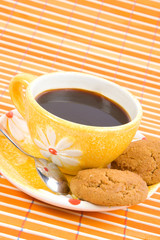 Cookies and cup with cofee on bamboo table-cloth
