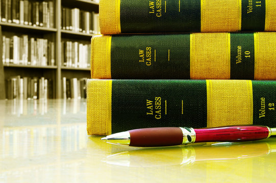Lawbooks stacked with pen, in a library