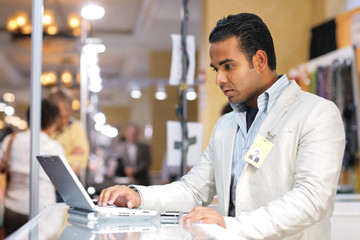 Young indian businessman using laptop computer at trade show.