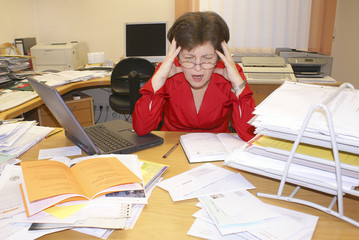 Stress im Büro, Frau sitzt angespannt am Schreibtisch