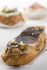 Chocolate eclair. Cupcakes in background.