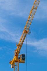 Bright yellow construction crane against clear blue sky.