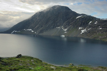 Obraz premium small cottage by the lake and mountain