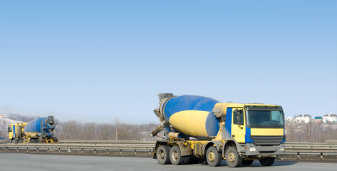 two identical  yellow concrete mixer trucks 