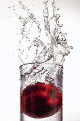 Apple splashing into a glass of water