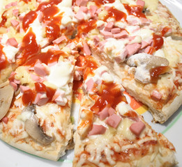 Incised pizza with mushrooms and sausages on white plate