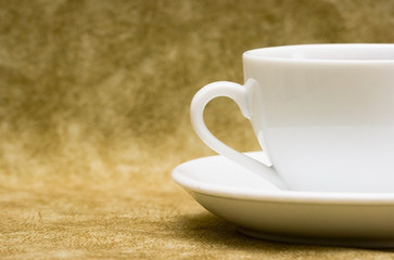 White cup with saucer over brown background