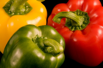 Red yellow and green Bell Peppers on a black background