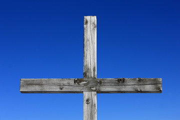 Holzkreuz vor blauem Himmelhintergrund