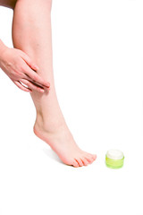 Woman body care - putting cream on her leg
