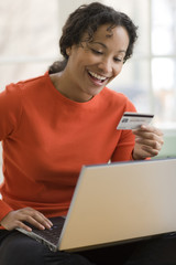 Black woman using credit card and laptop