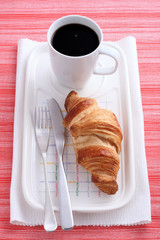 butter croissant and cup of black coffee on  red and white