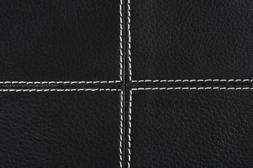 black leather background stitched up by white thread