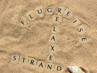 Flugreise, Strand u. Relaxen als Text im Sand