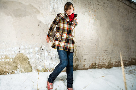 young girl pose in wool topcoat before a facture wall