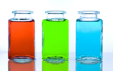 three glass bottles containing different color liquids
