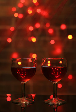 Two glasses of a red wine with warm lights in the background