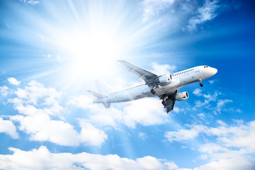 Airplane on blue sky and bright sun background