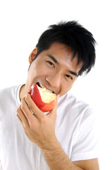 Young Asian man eating red apple close up