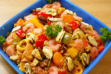 Paella with seafood, chicken and chorizo in blue bowl