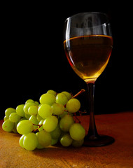 White grapes and glass of wine, on black