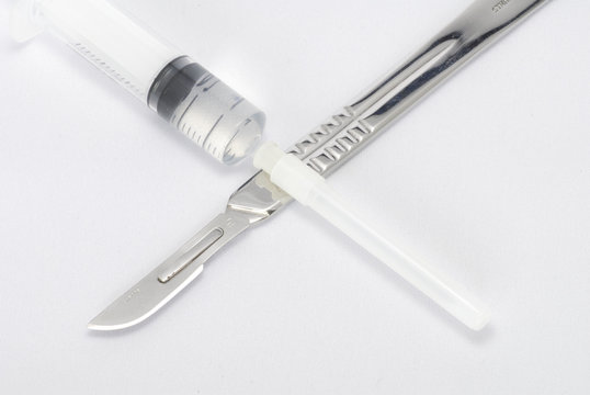 A Surgeon's scalpel and a syringe in a cross