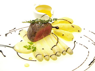 weißer spargel mit rinderfilet, kartoffeln und sauce hollandaise stilvoll auf weißem Hintergrund...