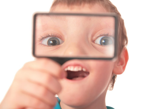 boy looks through  magnifier with surprise