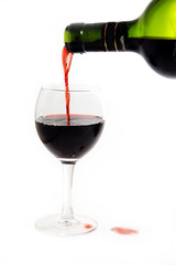 Green bottle pouring red wine into wineglass  over white