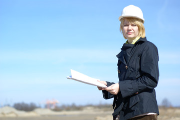 Architect with blueprints and hard hat at site