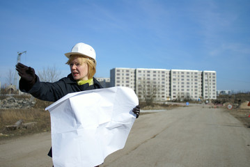 Architect with blueprints and hard hat at site