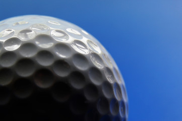 Closeup of a golf ball, on blue background