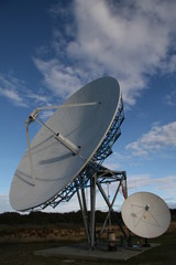 Two satellite dishes in front of a blue sky