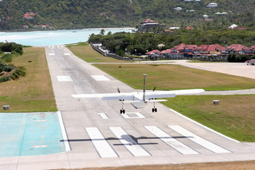 St. Barth: the short airstrip ends directly on the beach. - obrazy, fototapety, plakaty