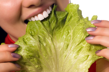 close up girl is eating a salad leaf