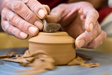Potter's hands  shaping  the bottom of a cup on a spinning wheel