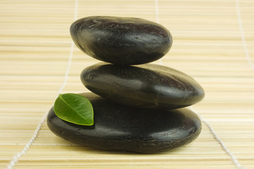 Fototapeta na wymiar Czarny zen kamienie i zielony liść bambusa
