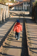 Jeune enfant marchant entre les rails d'une voie ferrée