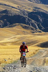 Fototapeta na wymiar Mountain biker racing on old road in desert