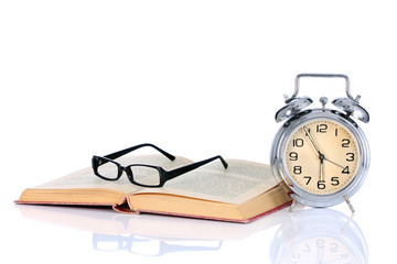 book with alarm clock and eyeglasses