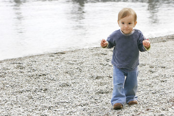 baby boy on empty pebble beach