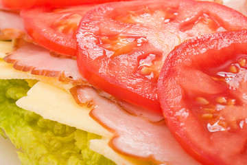 Lettuce, cheese, ham and tomatoes layered on a sandwich