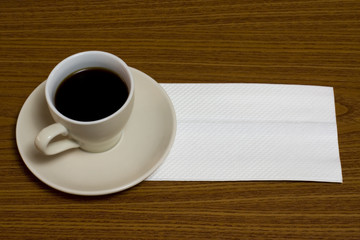 Obraz na płótnie Canvas A cup of coffee with napkin on a table
