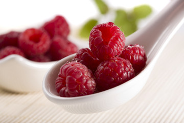 close-up of raspberries on white china spoon