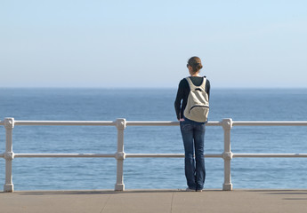Chica con mochila mirando al mar