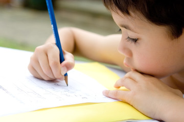 Young boy enjoying his handwriting homework, outdoors.