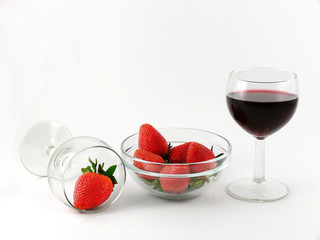 Wineglass of red wine and strawberry in a glass bowl