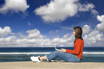 Woman working with a laptop on the beach